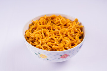 Close-up of fried instant noodles served in a floral ceramic bowl, isolated on white background
