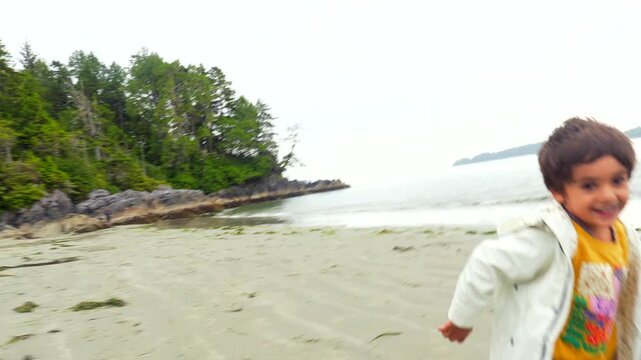 Young energetic child running freely along sandy tofino beach, experiencing joyful moments during summer vacation on vancouver island's scenic coastal landscape