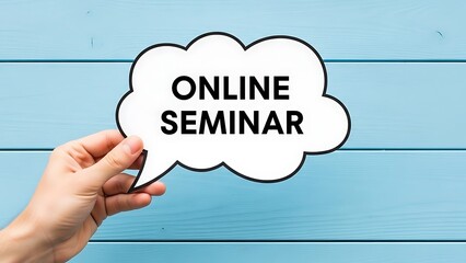 Hand holding a speech bubble sign announcing an online seminar against a bright blue wooden background