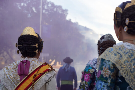 Fallas in Valencia. Faceless image of a group of Falleras with their backs to the camera, watching a masclet&agrave;, with smoke and gunpowder in the air.