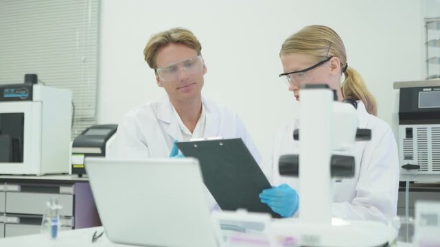 Scientists work in a laboratory discussing research methods and results on a computer