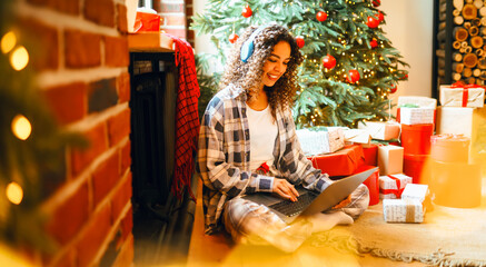 Cheerful woman with laptop and New Year's gifts is shopping online. A beautiful woman is having fun...