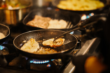 Professional chef multitasking at a busy gas stove, managing multiple pans during restaurant service, showing heat, pressure, coordination, and intense workflow inside a commercial kitchen.