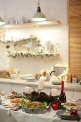 Christmas kitchen and dinner table with festive lights, candles, roasted chicken, and holiday decorations