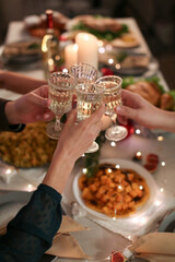 Clinking glasses with champagne during romantic Christmas dinner celebration