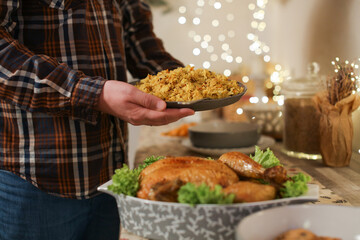 Man serving rice dish for Christmas dinner with roasted chicken and festive holiday table setting