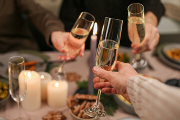 Pouring champagne at Christmas dinner table with candles and bokeh Christmas tree lights