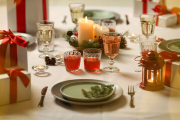 Christmas table with candles, drinks, pine branches and festive decor for holiday celebration