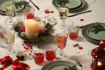 Christmas table with candles, drinks, pine branches and festive decor for holiday celebration