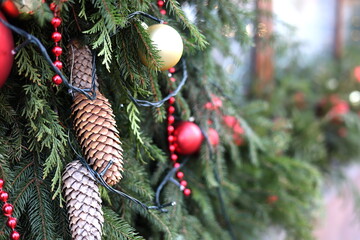 Cones on Christmas tree branches on a background of garlands and red balls and beads