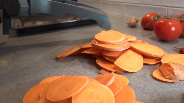 Stockholm, Sweden A home chef slices sweet potatoes on a Mandolin in a residential kitchen. 
