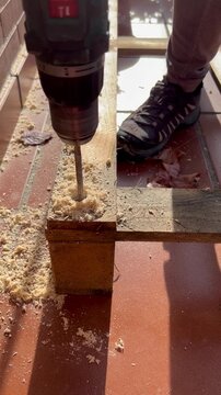 Proceso de perforaci&oacute;n de palets de madera con broca pala para crear una base estructural. Los agujeros permiten insertar tubos de pl&aacute;stico invernadero, mostrando trabajo vista semi lateral 