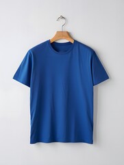Plain royal blue tshirt hanging on wooden hanger against light wall
