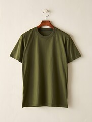 Plain olive green tshirt hanging on wooden hanger against light wall