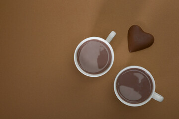 Pieces of bitter chocolate, spoon with cocoa powder and glass of cocoa drink on a brown vintage table.