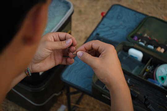 Primer plano de pescador preparando un anzuelo para pescar carpas. 