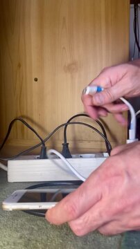 cargando tel&eacute;fono m&oacute;vil con cargador, cable y enchufe conectado en ladr&oacute;n