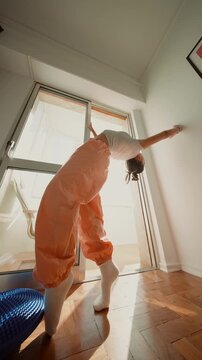 white performer holding arabesque pose by bright window