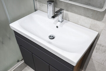 Modern bathroom vanity with white ceramic sink, chrome faucet, and drawers, set against a textured concrete wall, creating a clean, minimalist interior design