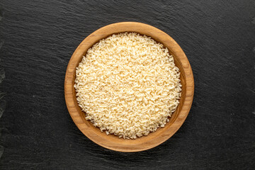 Coconut shavings in a wooden dish on a stone, top view, macro.