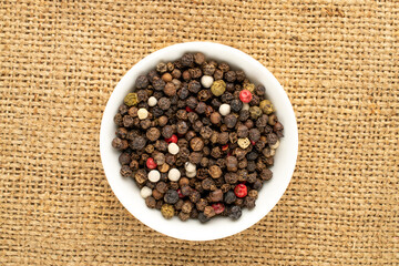 Allspice peas on jute fabric, macro, top view.