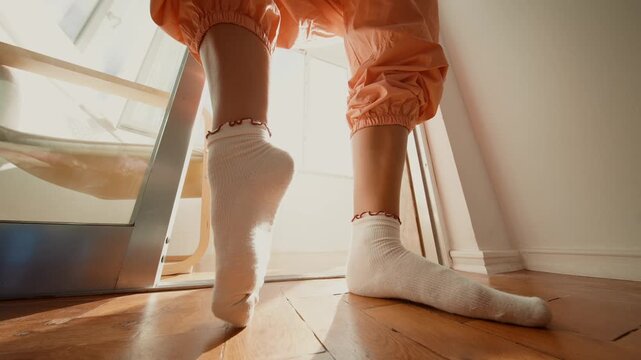 Peaceful domestic scene showing feet in orange joggers on sunlit balcony