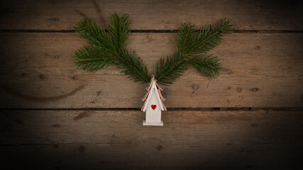 Christmas tree fir branch with winter decoration house on wooden background