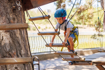 Child Navigating Rope Course in Adventure Park with Safety Gear