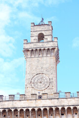 Obraz premium A close-up view of the clock tower in Montepulciano, Italy, showcasing the intricate design and architectural details against a clear blue sky.