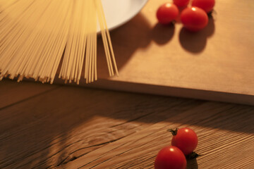 Part of the kitchen table with raw spaghetti and tomatoes