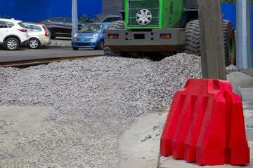 Road repair work. Red road barrier. Road equipment. Scattered gravel on the road.
