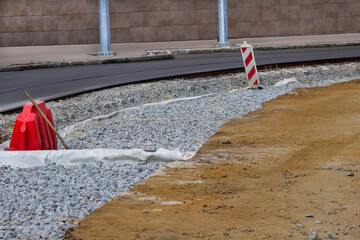 Tram line and road repairs. Gravel and soil on the road. Roadside warning signs.