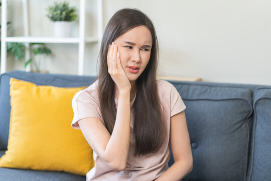Sensitive teeth, health care concept. Teeth pain and dentistry asian young woman suffer touching her cheek. Female feeling painful toothache. Unhappy feel bad, diseases in oral, ache nerve and molar.