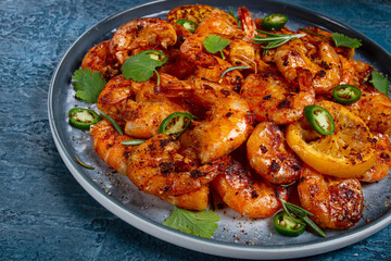 grilled shrimp, unpeeled, headless, with spices, on a dark blue table, homemade, no people,