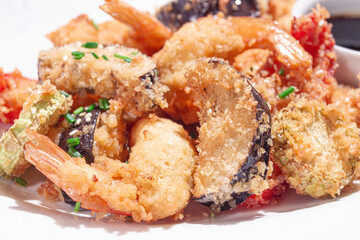 Shrimp and vegetable tempura, served with dipping sauce, on a white plate