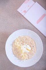 Poached egg and oatmeal porridge on white plate. Concept of healthy eating. Flat lay. Top view. Copy space.