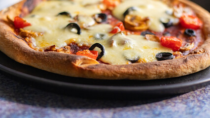 Freshly baked pizza with mozzarella cheese, olives and cherry tomatoes close up