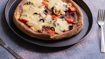 Pizza with Melted mozzarella Cheese and vegetable toppings served on Black Plate