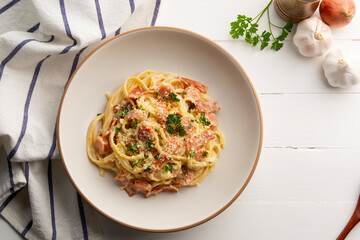 Fettuccine pasta with creamy carbonara sauce with pork sausage and bacon in a plate.Top view.