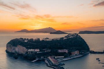 Coastal town buildings at sunset with mountains in the background. Nisida, Naples