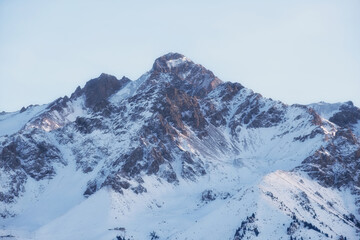 A snow-capped mountain peak against a blue sky. Beautiful winter landscape with sun, ideal for those traveling and outdoor activities