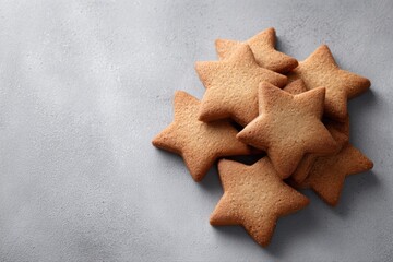 A clean, overhead flat lay of homemade, star-shaped cinnamon biscuits arranged geometrically on a simple light grey slate or concrete surface, focus on texture.