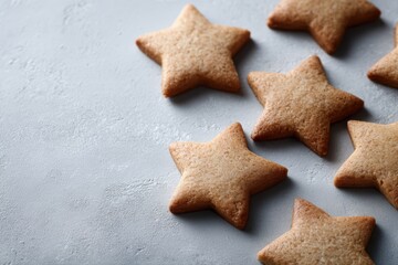 A clean, overhead flat lay of homemade, star-shaped cinnamon biscuits arranged geometrically on a simple light grey slate or concrete surface, focus on texture.