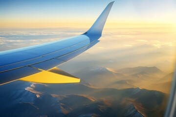 Breathtaking view of an airplane wing soaring above majestic mountains at sunrise over a vast landscape