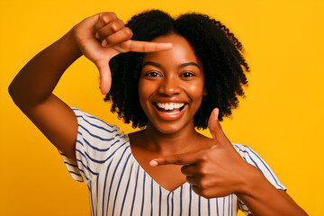 Joyful young Black woman framing her smile with her hands against a vibrant yellow background, capturing the moment.