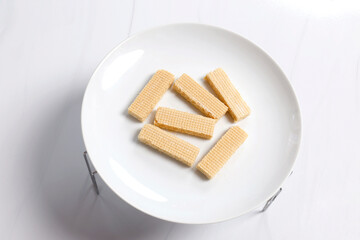 Crispy vanilla wafer sticks on a white plate, Crispy wafer sticks arranged neatly on a white plate in bright soft lighting, showing texture and simple minimal food styling