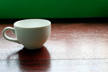 White ceramic cup on wooden table with natural light, creating a calm minimal atmosphere suitable for coffee, tea, or lifestyle concepts