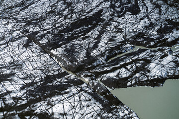 Aerial view of a glacier in Iceland showing striking natural patterns, cracks, and dark volcanic ash layers