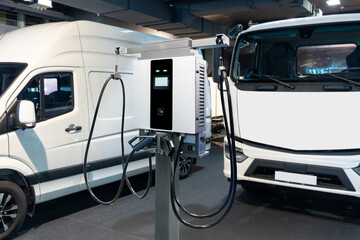 Electric vehicles charging station on a background of trucks and van