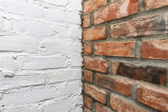 Corner of interior wall with contrast between white painted bricks and bare red brick masonry, construction background showing renovation, loft style design and modern industrial interior texture 